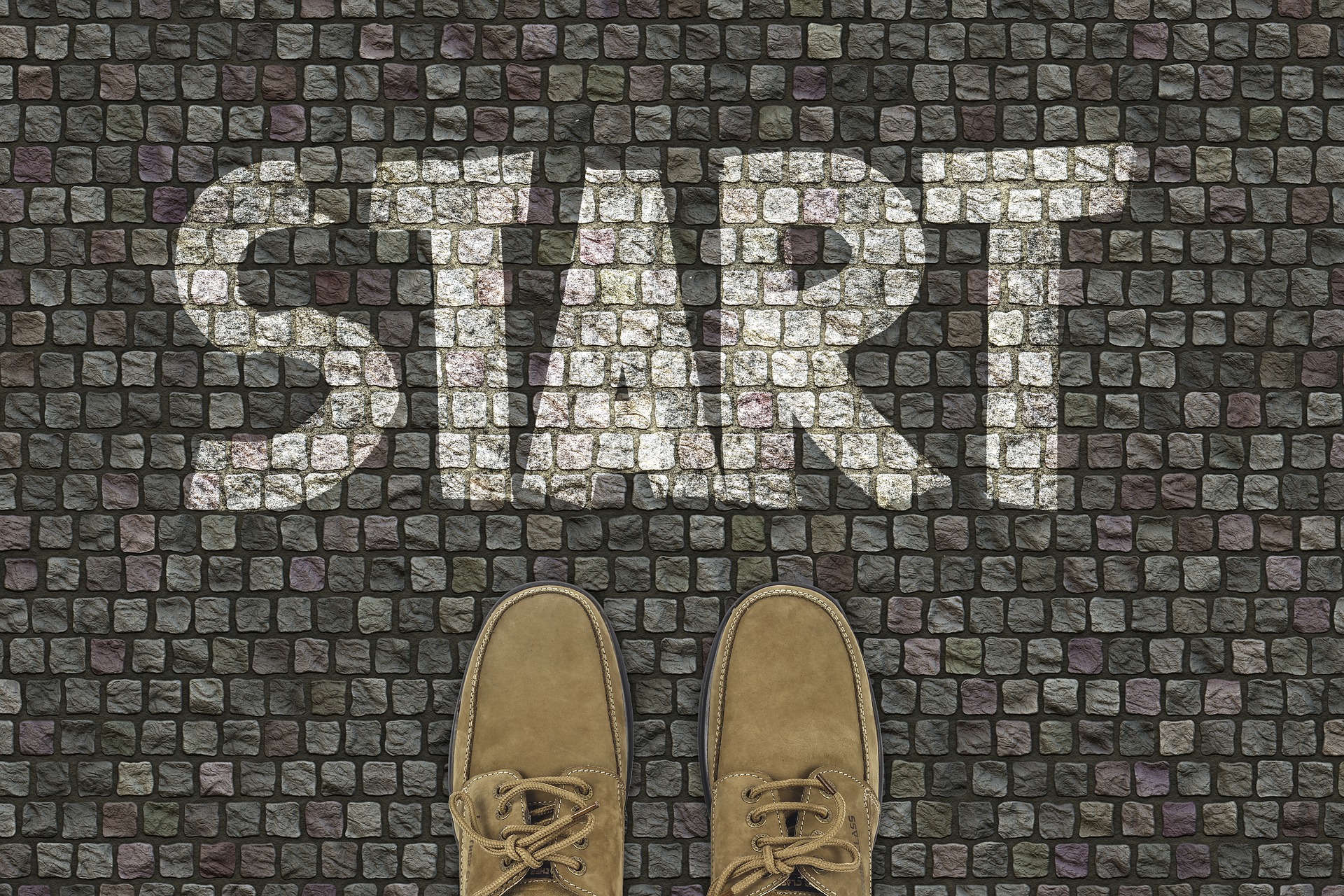 Straßenpflaster von oben gesehen mit zwei Schuhen und dem Text "Start"